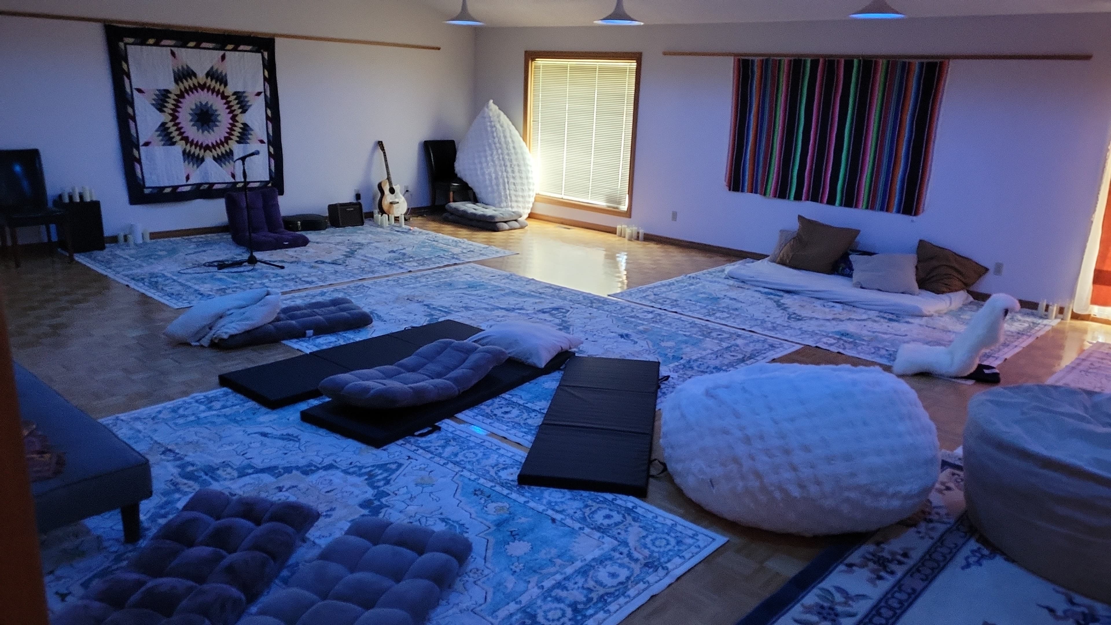 The great room at dusk with warm lamps, star quilt, and floor cushions